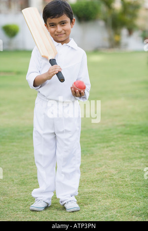 Ritratto di un ragazzo tenendo un cricket bat e una sfera di cricket Foto Stock