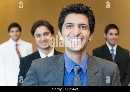 Close-up di un imprenditore sorridente con tre dirigenti aziendali dietro di lui Foto Stock