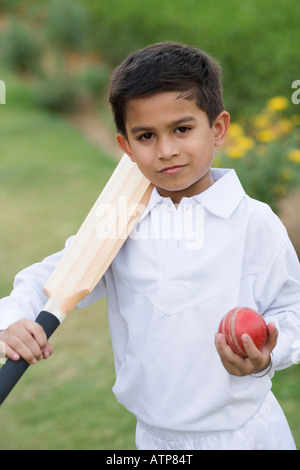 Ritratto di un ragazzo tenendo un cricket bat e una sfera di cricket Foto Stock