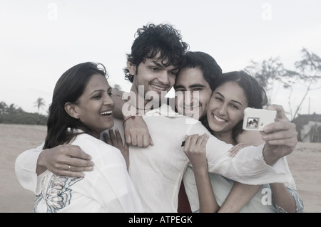 Giovane uomo di prendere una fotografia di se stesso con i suoi tre amici Foto Stock