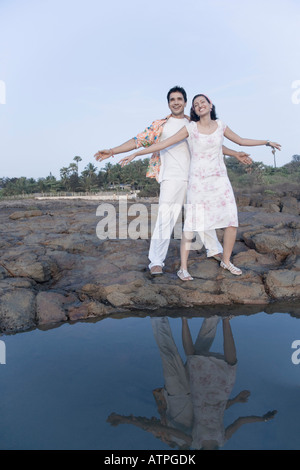 Coppia giovane in piedi con le braccia tese e sorridente Foto Stock