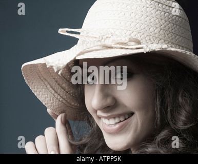 Ritratto di una giovane donna che indossa un cappello di paglia e sorridente Foto Stock