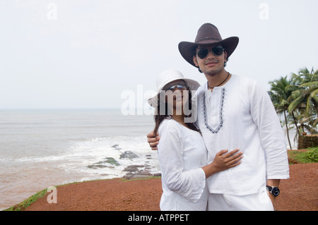 Coppia giovane permanente sulla spiaggia Foto Stock