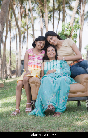 Coppia donna seduta con le sue due figlie in poltrona Foto Stock
