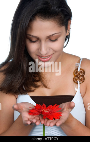 Giovane e bella ragazza adolescente guardando ref gerbera fiore Foto Stock