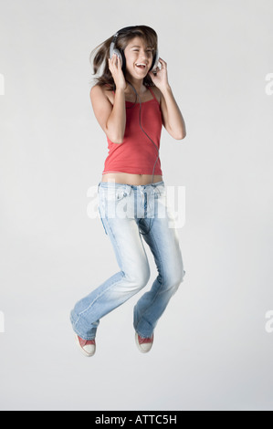 Giovane donna ascoltando musica e jumping Foto Stock