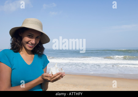 Ritratto di una giovane donna che mantiene un guscio e sorridente Foto Stock