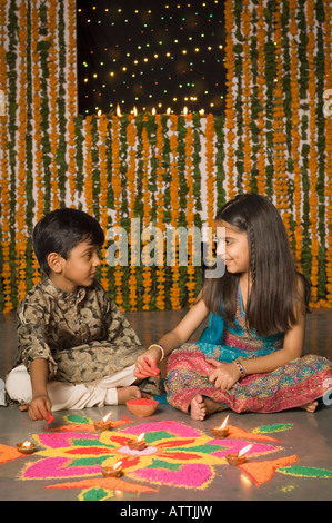 Ragazzo e sua sorella rendendo rangoli Foto Stock