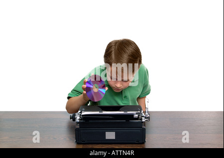 Ragazzo che cerca di scoprire dove il dvd va in questa strana concezione portatile della gioventù e tecnologia retrò Foto Stock