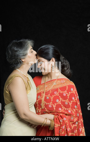 Profilo laterale di una donna matura baciare sulla fronte della figlia Foto Stock