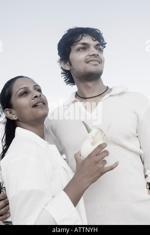 Giovane uomo in piedi con una giovane donna con in mano un bicchiere di cocktail Foto Stock