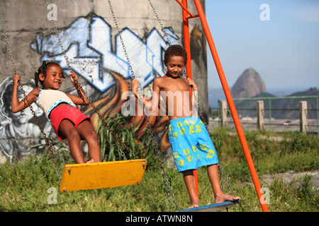 I bambini giocano su altalena in Rio de Janeiro favela baraccopoli con graffiti, Brasile, Sud America Foto Stock