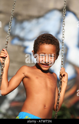 I bambini giocano su altalena in Rio de Janeiro favela baraccopoli con graffiti, Brasile, Sud America Foto Stock