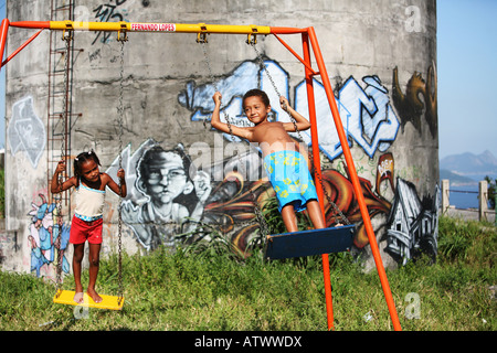 I bambini giocano su altalena in Rio de Janeiro favela baraccopoli con graffiti, Brasile, Sud America Foto Stock