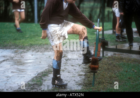 Spegnimento di pulizia sporchi stivali di rugby dopo una partita. Foto Stock