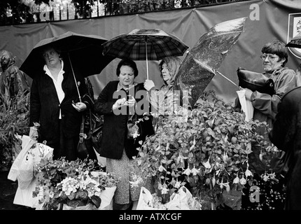 I visitatori di lasciare il Chelsea Flower Show sotto la pioggia Foto Stock