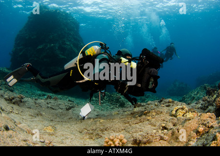 Scott Blain linee fino su una scogliera con la sua videocamera HD in un alloggiamento di cancelli, Costa di Kona, Hawaii. Foto Stock