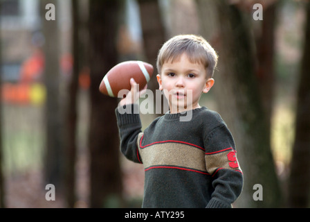 Elementi maschio di una famiglia estesa di giocare a calcio nel loro cortile anteriore sul giorno del Ringraziamento Foto Stock