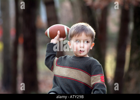 Elementi maschio di una famiglia estesa di giocare a calcio nel loro cortile anteriore sul giorno del Ringraziamento Foto Stock