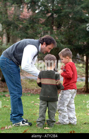 Elementi maschio di una famiglia estesa di giocare a calcio nel loro cortile anteriore sul giorno del Ringraziamento Foto Stock