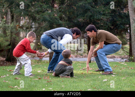 Elementi maschio di una famiglia estesa di giocare a calcio nel loro cortile anteriore sul giorno del Ringraziamento Foto Stock