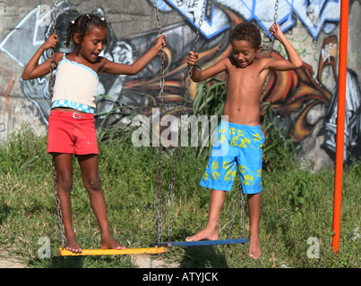 I bambini giocano su altalena in Rio de Janeiro favela baraccopoli con graffiti, Brasile, Sud America Foto Stock