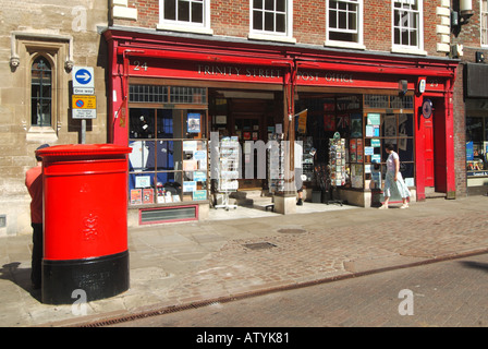 Donna acquirente fuori dal negozio dell'ufficio postale di Trinity Street a Cambridge città universitaria & rosso ovale profilo postale lettera casella Cambridgeshire Inghilterra Regno Unito Foto Stock
