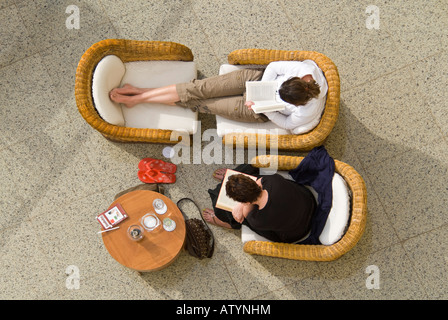 Sopraelevata orizzontale in prossimità di due signore rilassarsi sulle sedie di vimini e la lettura di libri al sole Foto Stock