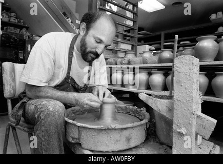 Un vasaio opere gettando vasi di ceramica nel suo studio di produzione quasi perfetta di duplicati di uno dei suoi disegni. Vetri seguiranno. Foto Stock