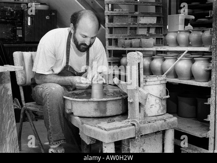 Un vasaio opere gettando vasi di ceramica nel suo studio di produzione quasi perfetta di duplicati di uno dei suoi disegni. Vetri seguiranno. Foto Stock