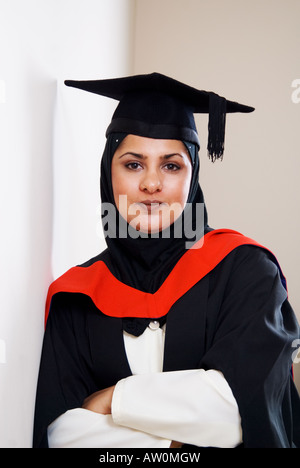 Ritratto di donna musulmana che indossa il cappuccio di graduazione e camice bracci ripiegati Foto Stock