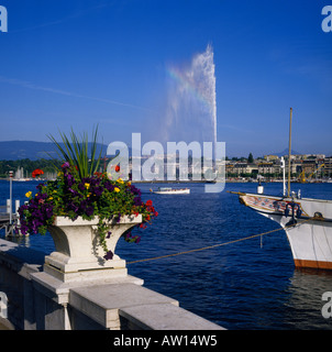 Guardando attraverso un balcone in pietra e urna piantati con viola giallo e rosso dei fiori per il getto di acqua sul Lago di Ginevra Svizzera Foto Stock