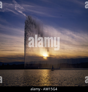 Guardando attraverso la superficie calma del lago di Ginevra al tramonto al potente fontana acqua & wispy nuvole bianche Ginevra Svizzera Foto Stock