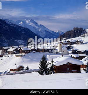 Scatola di cioccolatini di inverno con vista chiesa guglia e neve spesso nel villaggio di Bienne Goms Vallese Svizzera meridionale Foto Stock