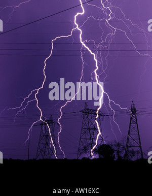 Un fulmine contro un viola scuro sky in prossimità di linee elettriche e di poli di potenza elettrica o torri durante il monsone di Tucson in Arizona Foto Stock