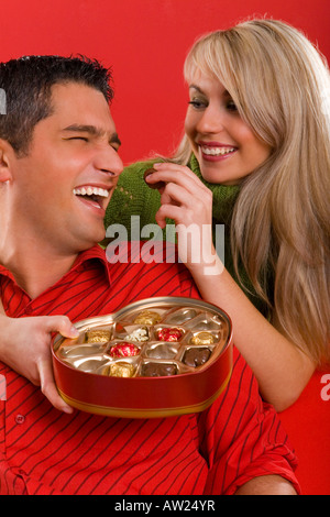 Giovane innamorato giovane donna è uomo di alimentazione da cioccolato e sorridente vista frontale Foto Stock