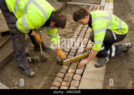 Gli uomini al lavoro, recante un incrocio veicolo, pavimentato. Ingegneria stradale persone.La salute e la sicurezza stradale di verniciatura Foto Stock