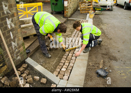 Gli uomini al lavoro, recante un incrocio veicolo, pavimentato. Ingegneria stradale persone.La salute e la sicurezza stradale di verniciatura Foto Stock