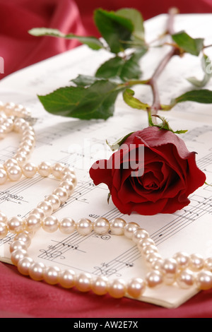 Red Rose e filo di perle giacente sul foglio di musica Foto Stock