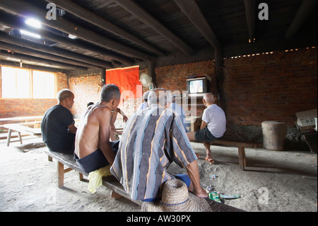 Gli uomini anziani guardando la televisione nel villaggio rurale, Chenyang, Guangxi, Cina Foto Stock