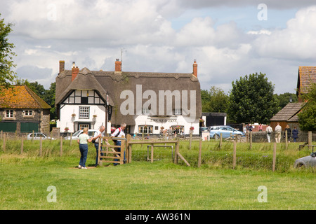 Walkers passando attraverso un bacio gate nella parte anteriore del Red Lion pub di Avebury Foto Stock