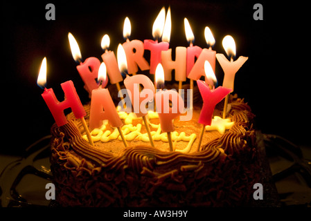 Le candele accese dicendo Buon compleanno su una torta al cioccolato Foto Stock
