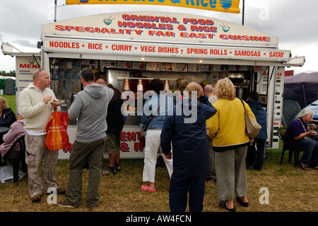 La gente in coda per cibo a oriental nooles fast food catering mobile unità o caravan in corrispondenza di un evento esterno Foto Stock
