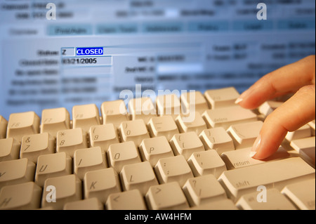 Donna presse a mano 'RETURN' su una scheda a chiave e il monitor di un computer in background mostra la parola 'chiuso'. Foto Stock