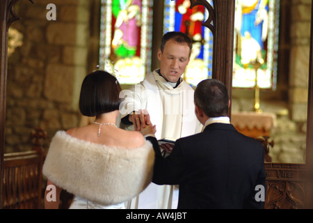 Un paio di sposarsi con un pieno di cerimonia nuziale e il vicario in una chiesa a Nord Yorkshire Modello rilasciato Foto Stock
