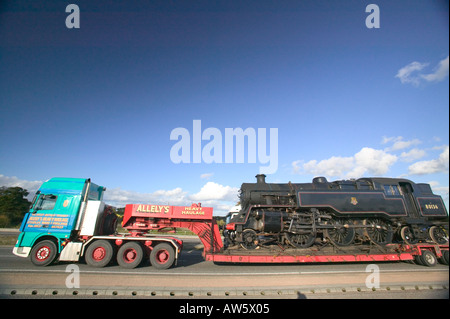 Locomotiva a vapore treno essendo trasportati su strada mediante un caricatore basso, Leicestershire, Regno Unito Foto Stock