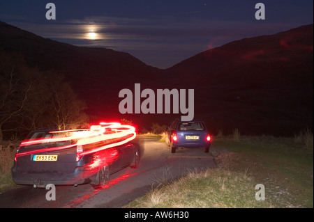 Vetture Hardknott discendente passano la notte illuminata da una luna piena, Lake District, Cumbria, Regno Unito Foto Stock