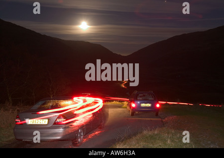 Vetture Hardknott discendente passano la notte illuminata da una luna piena, Lake District, Cumbria, Regno Unito Foto Stock