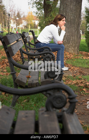 Una giovane donna seduta su un banco di lavoro nel pensiero di stazionamento Foto Stock