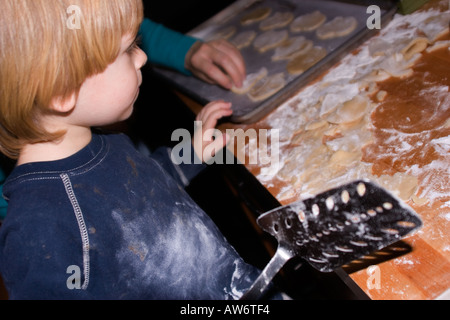 Little Boy aiutare sua madre cuocere i biscotti in forno. Foto Stock